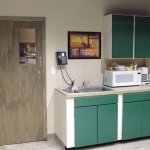 Close up of break room showing poster both through door window and inspirational one over sink.  Cabinets, lockers and refrigerator were repainted. Floor was painted in shop and then laid with high gloss finish. Woodwork was a wash over raw wood.